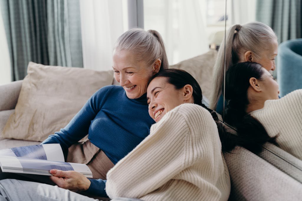A joyful moment between a mother and daughter embracing each other on a sofa at home.